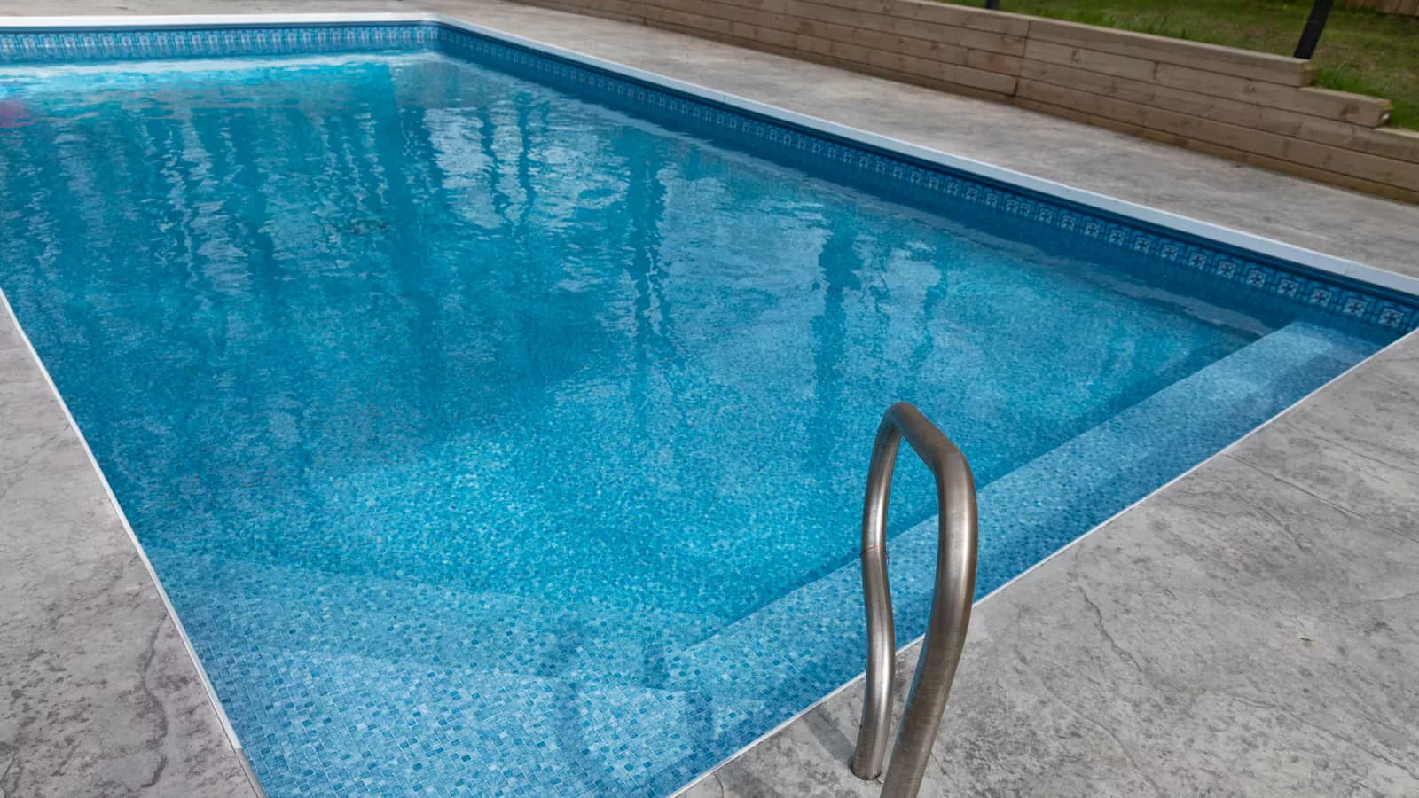 Piscina de fibra azul com água limpa e borda clara em área externa