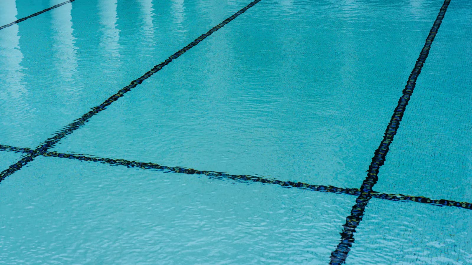 Piscina com piso de azulejos e água azul e cristalina, pronta para o verão