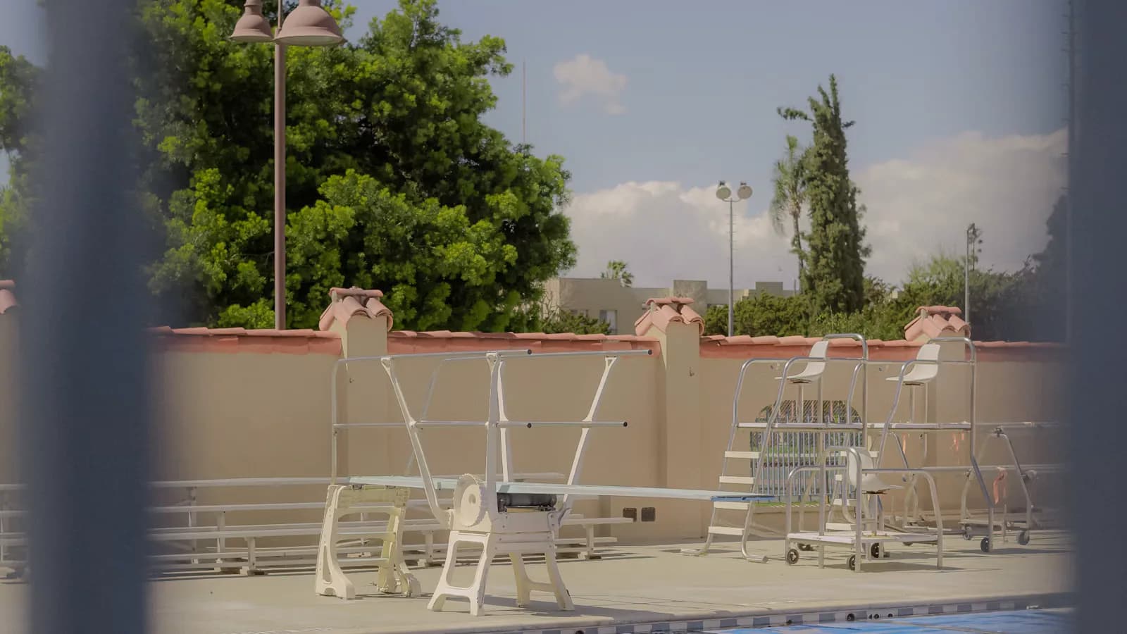 Piscina vazia com capa térmica azul e trampolins brancos ao fundo